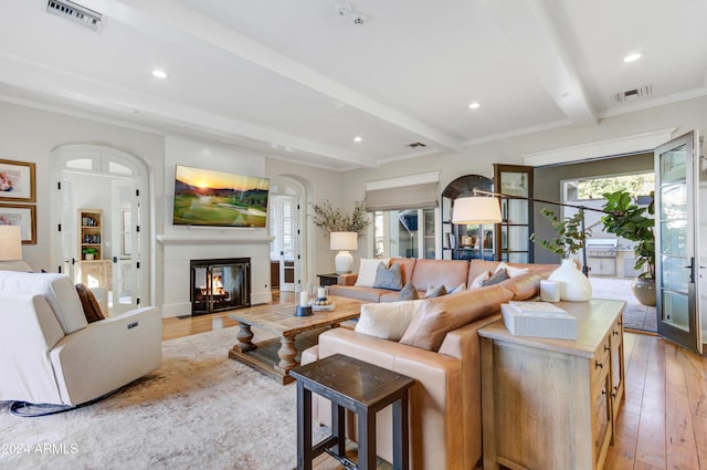 living room with beam ceiling, light hardwood / wood-style flooring, and crown molding