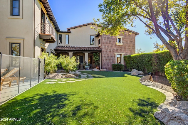 rear view of property with a yard, a patio area, and a balcony