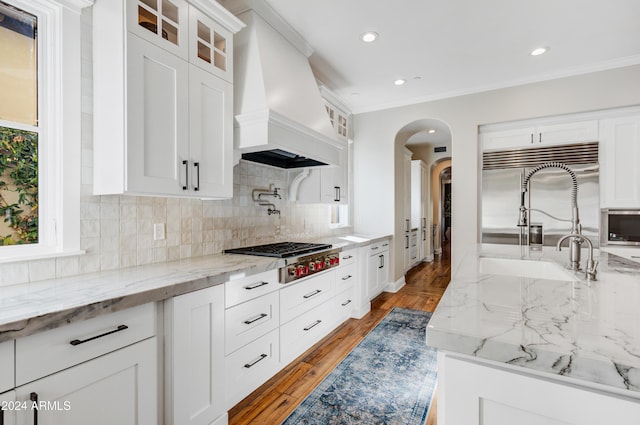 kitchen featuring stainless steel appliances, white cabinetry, ornamental molding, and custom exhaust hood