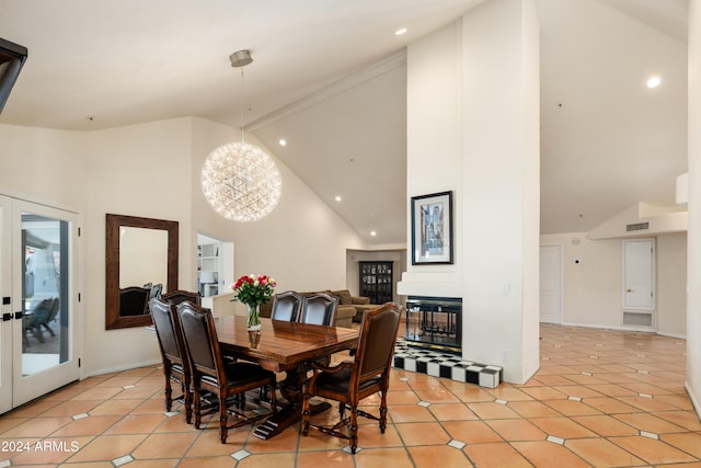 dining area featuring a multi sided fireplace, light tile patterned floors, high vaulted ceiling, and an inviting chandelier