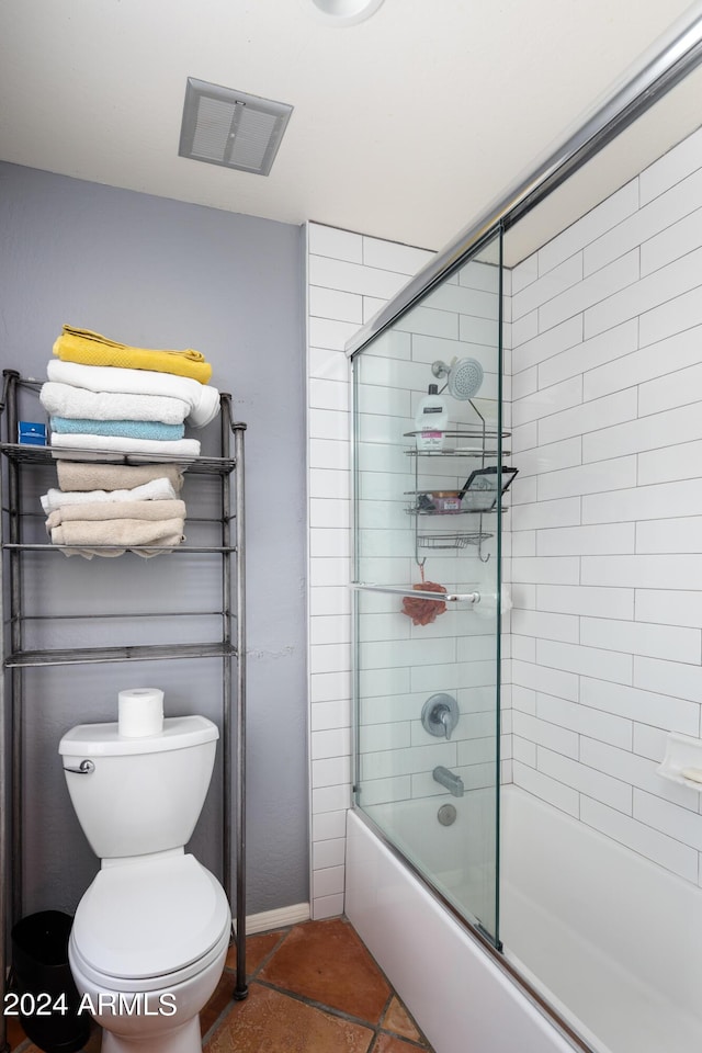 bathroom featuring combined bath / shower with glass door, tile patterned flooring, and toilet