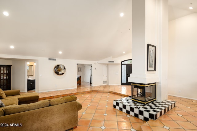 living room featuring a multi sided fireplace, light tile patterned flooring, and vaulted ceiling