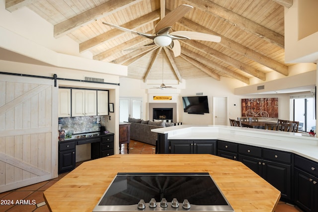 kitchen with tasteful backsplash, a barn door, beamed ceiling, and butcher block counters