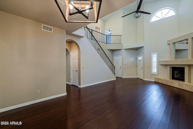 unfurnished living room with a high end fireplace, a towering ceiling, dark hardwood / wood-style flooring, and ceiling fan