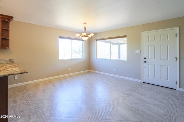 unfurnished dining area featuring a wealth of natural light and a chandelier