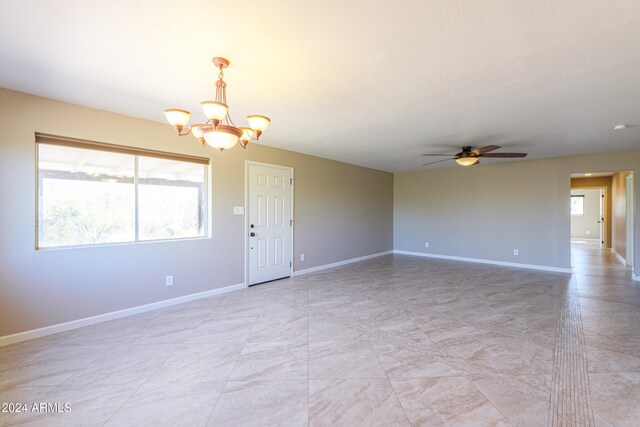 spare room with ceiling fan with notable chandelier