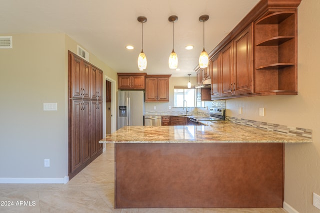 kitchen featuring kitchen peninsula, appliances with stainless steel finishes, decorative light fixtures, and light stone countertops