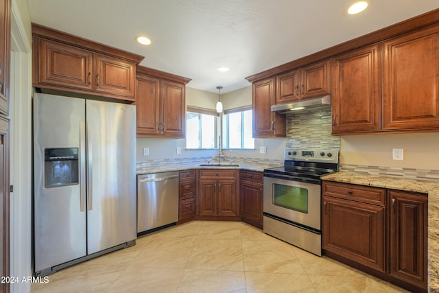 kitchen with light stone counters, stainless steel appliances, backsplash, hanging light fixtures, and sink