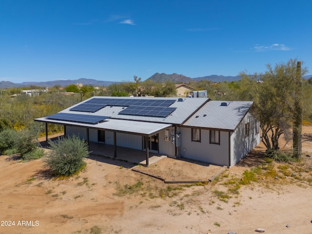 back of house featuring a patio area, solar panels, and a mountain view