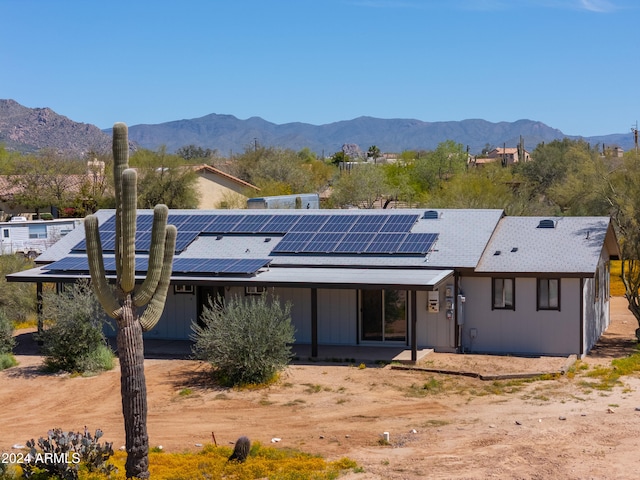 back of property with a mountain view and solar panels