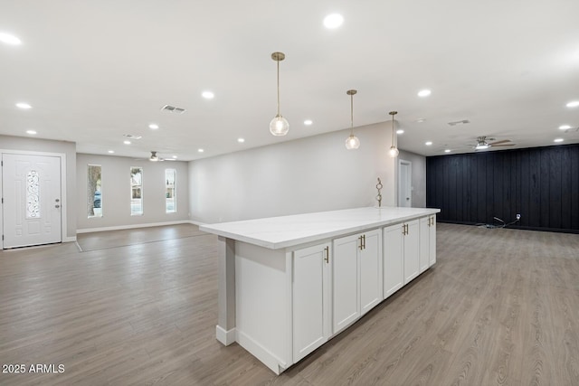 kitchen featuring open floor plan, light wood-style flooring, visible vents, and light stone countertops