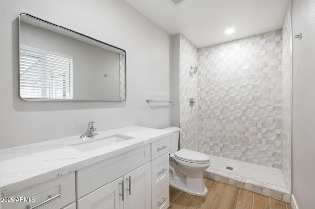 full bath featuring recessed lighting, toilet, wood tiled floor, vanity, and tiled shower