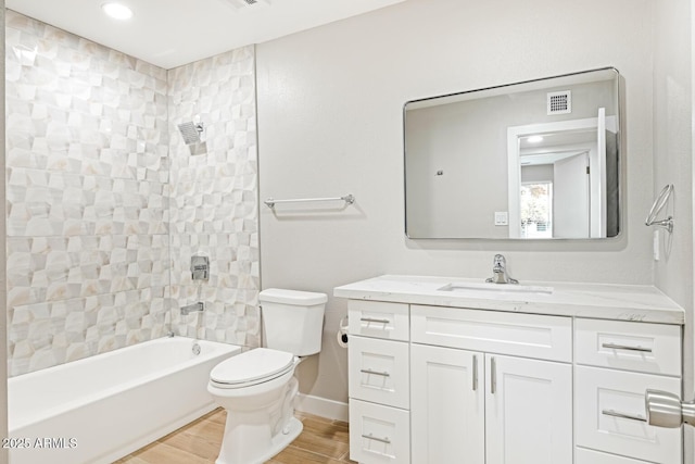 bathroom featuring visible vents, bathing tub / shower combination, toilet, wood finished floors, and vanity