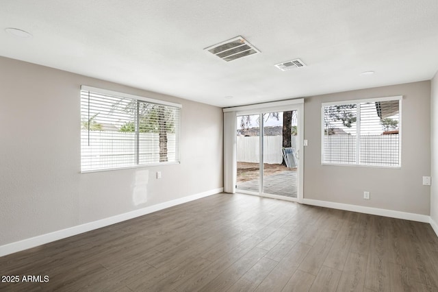 unfurnished room with visible vents, baseboards, and wood finished floors