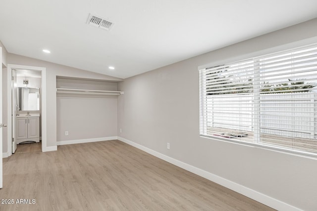 unfurnished bedroom featuring light wood-type flooring, baseboards, and vaulted ceiling