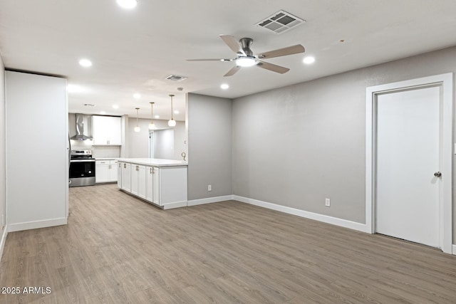 kitchen with light wood-type flooring, electric range, visible vents, and wall chimney range hood