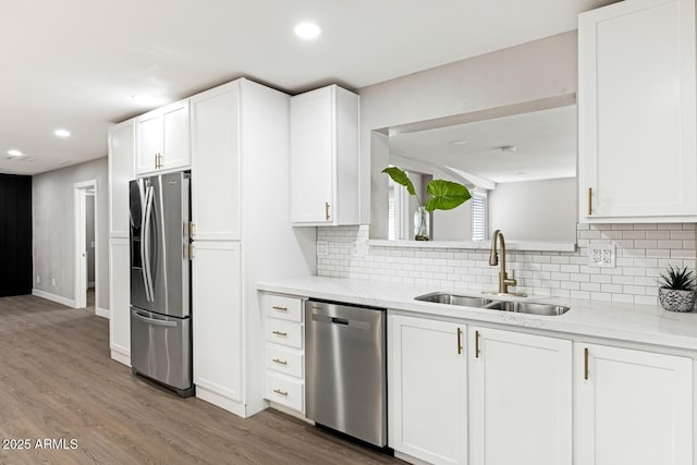 kitchen with recessed lighting, stainless steel appliances, wood finished floors, a sink, and white cabinets