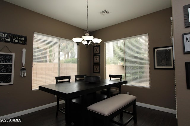 dining area with dark wood-type flooring and a chandelier