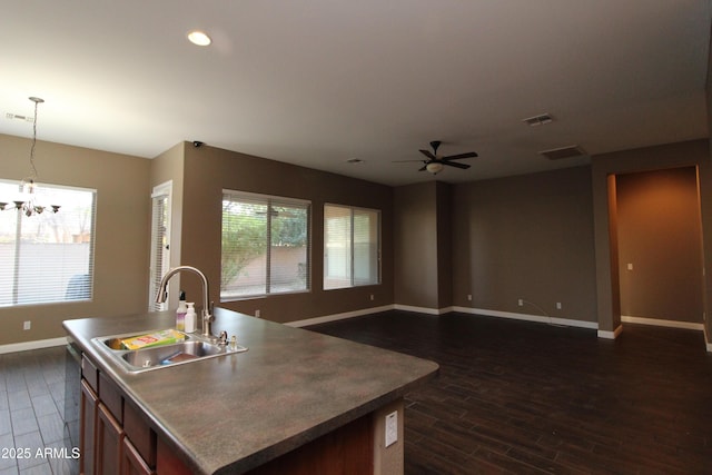 kitchen with dark wood-type flooring, a kitchen island with sink, sink, and hanging light fixtures