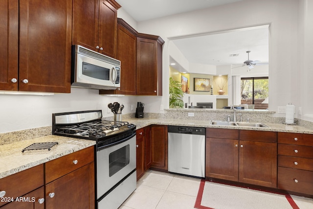 kitchen with light tile patterned flooring, appliances with stainless steel finishes, light stone countertops, and sink