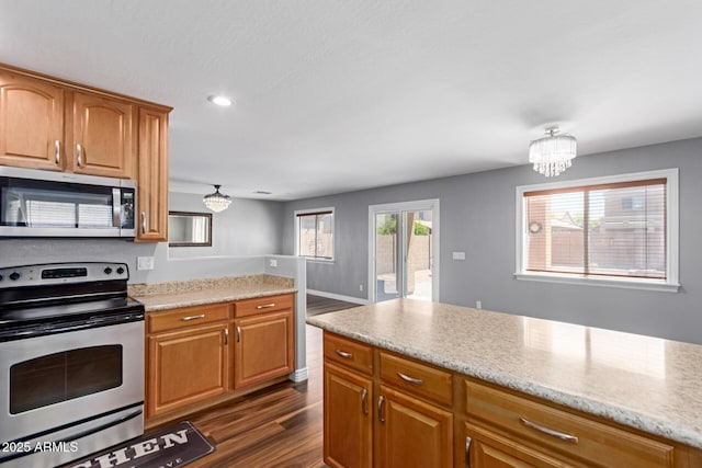 kitchen featuring stainless steel appliances, a chandelier, dark wood-type flooring, recessed lighting, and brown cabinetry