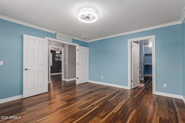unfurnished bedroom with baseboards, ornamental molding, wood finished floors, and a spacious closet
