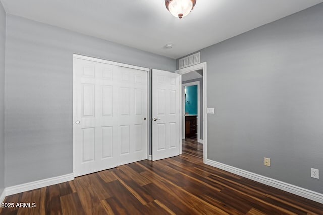 unfurnished bedroom featuring dark wood finished floors, baseboards, and a closet
