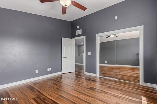 unfurnished bedroom featuring wood finished floors, baseboards, a ceiling fan, a closet, and vaulted ceiling