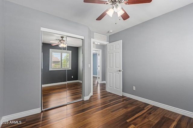 unfurnished bedroom with wood finished floors, a closet, baseboards, and a ceiling fan