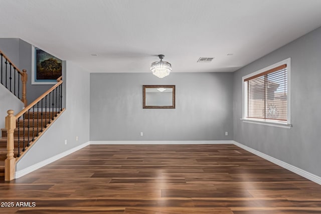 spare room featuring wood finished floors, stairway, and baseboards