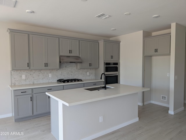 9408 E Sequence Ave, Mesa, AZ 85212 - kitchen with gray cabinetry, appliances with stainless steel finishes, under cabinet range hood, and decorative backsplash