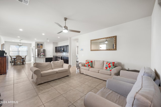 tiled living room with ceiling fan with notable chandelier