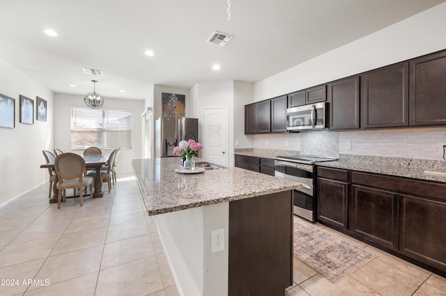 kitchen featuring dark brown cabinets, a center island, tasteful backsplash, hanging light fixtures, and stainless steel appliances