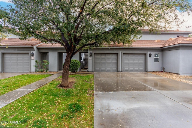 townhome / multi-family property featuring concrete driveway, a front lawn, a tile roof, and stucco siding