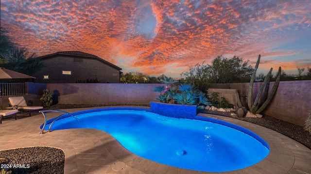 pool at dusk with a patio area