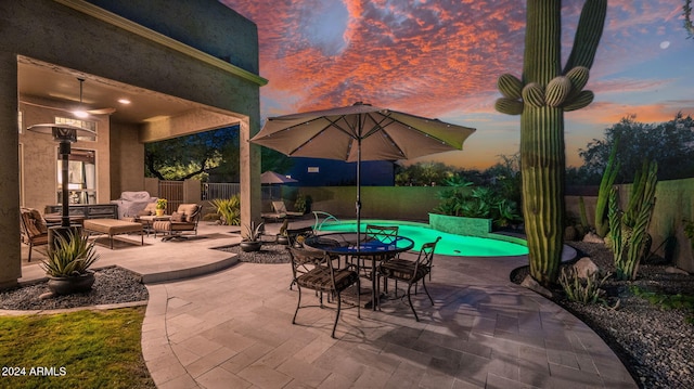 patio terrace at dusk with a fenced in pool