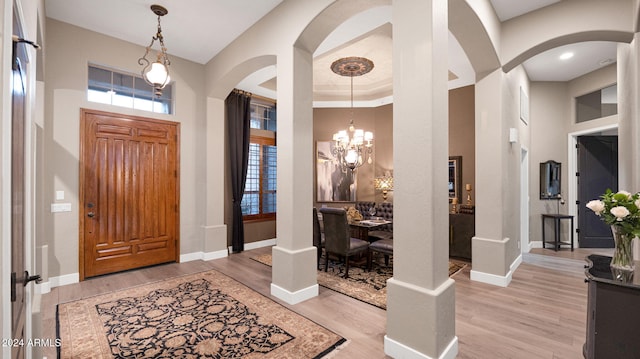 foyer entrance featuring a towering ceiling, an inviting chandelier, and light hardwood / wood-style flooring