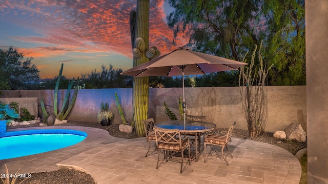 pool at dusk with a patio area