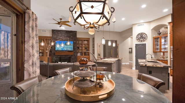 dining room with sink, ceiling fan, built in shelves, a fireplace, and light hardwood / wood-style floors