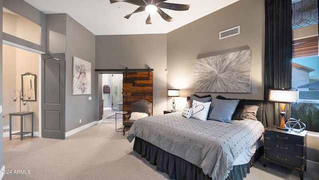 carpeted bedroom with a barn door and ceiling fan