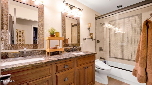 full bathroom with hardwood / wood-style flooring, toilet, combined bath / shower with glass door, and vanity