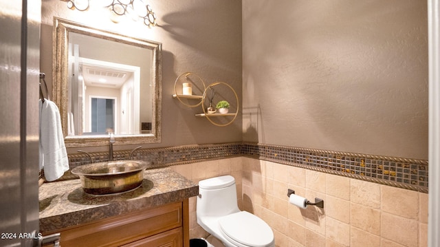 bathroom featuring vanity, tile walls, and toilet