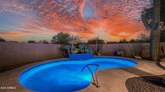 pool at dusk with a patio area