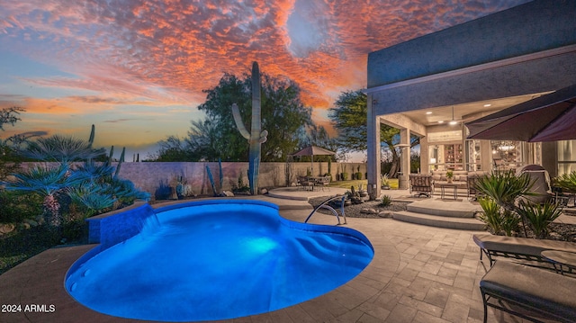 pool at dusk with a patio area