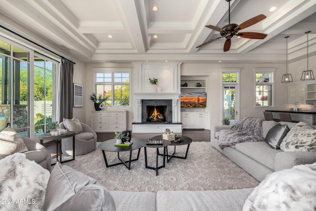 living room featuring beamed ceiling, ceiling fan, ornamental molding, and coffered ceiling