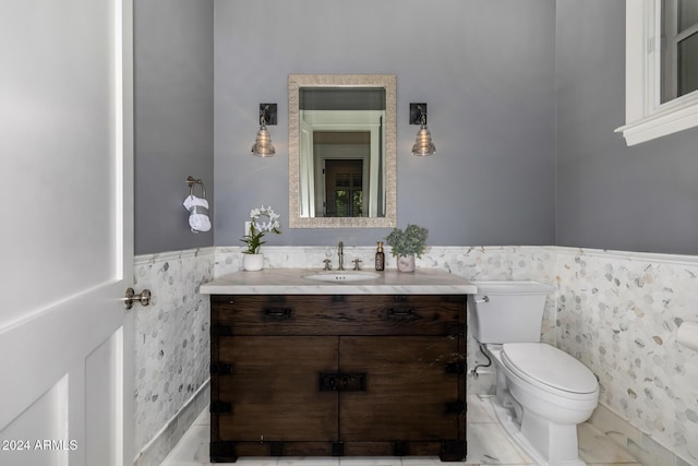 bathroom featuring vanity, toilet, and tile walls