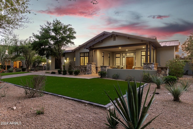 back house at dusk with a lawn