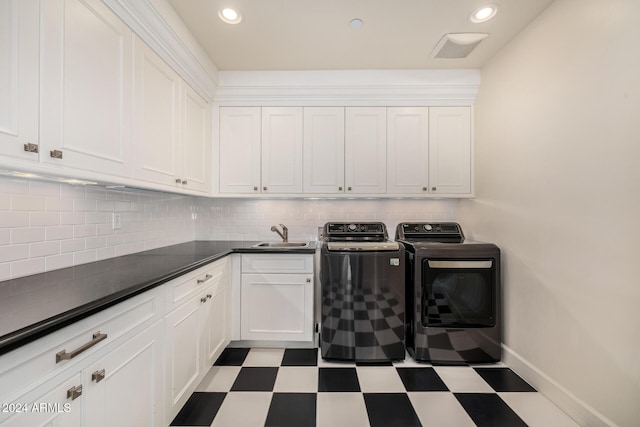 clothes washing area with washer and clothes dryer, cabinets, and sink