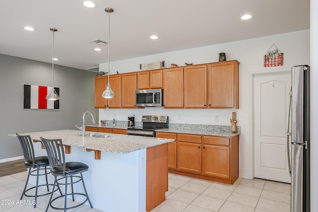 kitchen with a center island with sink, appliances with stainless steel finishes, hanging light fixtures, and sink