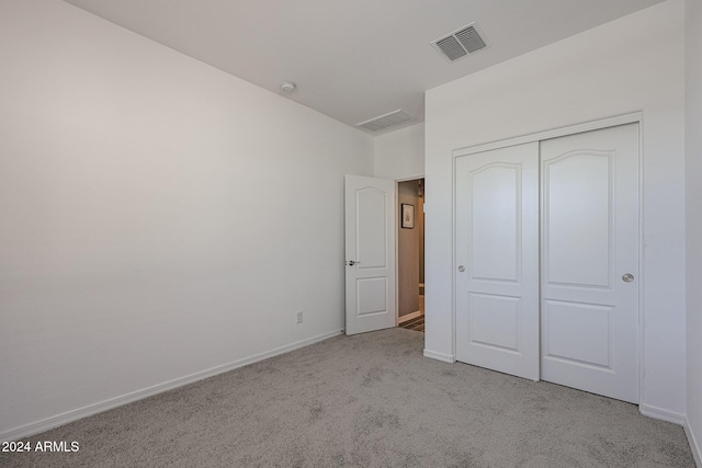 unfurnished bedroom featuring a closet and light colored carpet